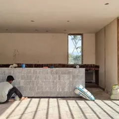 An artisan puts the finishing touches on a custom-designed bar at our Alibaug project. The bar front is clad in vertically laid marble tiles, a detail we refined through on-site collaboration.