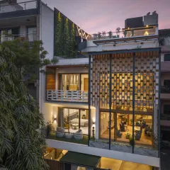 The Screen House is structured across four levels, with the stilt floor designed as an entertainment hub. This evening view shows the seamless blend of leisure spaces with the home's primary residential functions, all visible through the open façade.