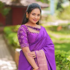 A smiling portrait of the model, giving a clear view of the front of the embroidered purple blouse.