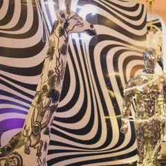 A close-up of the unique decor elements, including a hand-painted giraffe statue and a disco-ball mannequin against a psychedelic backdrop. We source and create props that make a brand's event truly one of a kind.