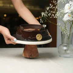 Presenting a cake is part of the joy. Here, my Belgium Chocolate Cake is held aloft, showcasing its rich, dark glaze and the signature 'Z' emblem that marks it as one of my creations.