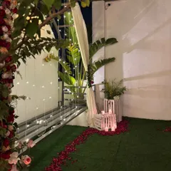 A romantic terrace setup at night, with a floral arch, fairy lights, and candles creating a magical ambiance for a proposal or anniversary.