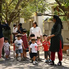 We're off on an adventure! The children are holding onto a rope as we take a nature walk through the neighborhood. This keeps everyone together and turns a simple walk into a team expedition.