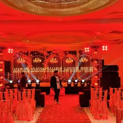 We use professional lighting to completely change the mood of a space. Here, a sangeet stage is bathed in dramatic red light, with intricate candle walls and spotlights creating a high-energy, club-like atmosphere perfect for a night of dancing.