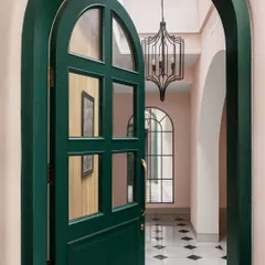 The entrance to the Quiet Ornate home makes a bold first impression. We chose a striking emerald green for the arched door, which opens into a skylit foyer with classic marble inlay floors, setting a tone of understated drama.