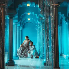 A regal portrait in a stunning blue hall, framed by shimmering crystal curtains. The unique color palette and lighting create a magical, almost surreal atmosphere for this elegant pre-wedding photo.