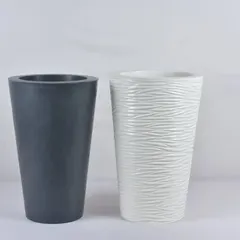 Two tall, cylindrical fiber planters. One has a smooth, dark grey finish, while the other has a textured white design, showing the variety of styles we offer.