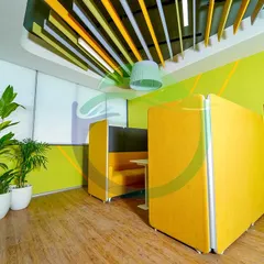 The same office space, but with a vibrant yellow and lime green color scheme. The tall Bird of Paradise and palm plants in white planters complement the bright, energetic feel of this collaborative pod.