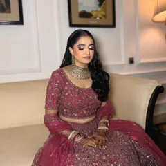 A close-up of a stunning reception bride. The soft glam makeup features a silver-toned smokey eye and a neutral pink lip, which beautifully complements her heavily embellished pink lehenga and silver jewelry.