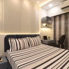 A full view of the Bhayandar West master bedroom, showing the integrated study nook next to the bed. The design uses fluted wall panels and cove lighting to create a calm and sophisticated environment.