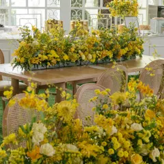 Tables overflowing with arrangements of yellow flowers, creating a lush, garden-like feel within the Haldi venue.