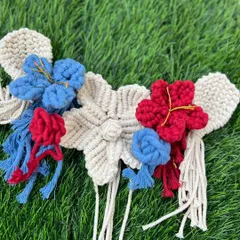 A collection of my handmade macrame flowers in red, blue, and cream. Each one is knotted by hand with intricate detail.