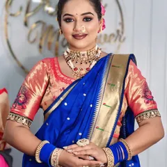 This look, named 'Chandrika', features a beautiful smile and traditional jewelry. The focus is on creating a radiant complexion with a soft pink lip that complements the royal blue saree.