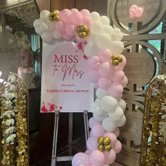 A lovely welcome sign for a 'Miss to Mrs' bridal shower. The personalized sign is adorned with a pink and white balloon garland, setting a sweet and celebratory tone for the event.