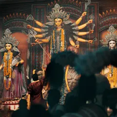 Faith is unseen but felt. A devotee stands before the magnificent idol of Goddess Durga, a moment of personal connection amidst the large crowd.
