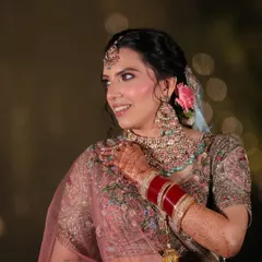 A close-up of Muskaan's radiant smile. Her makeup features soft pink eyeshadow and a flawless base, perfectly complementing the delicate embroidery on her pastel lehenga.