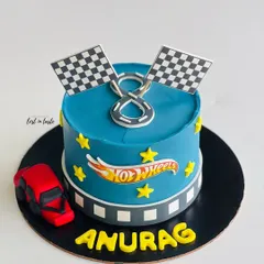 A Hot Wheels themed cake for a young racing fan. This design features a vibrant blue buttercream, the Hot Wheels logo, checkered flags, and a toy car.