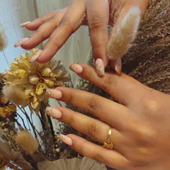 A close-up of a beautiful bridal nail set. These extensions feature a natural pink base with scattered gold flakes, creating a subtle yet festive look perfect for a wedding celebration.