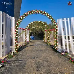 A series of classic floral arches made with red and white roses, creating an elegant and timeless pathway for a wedding entrance.