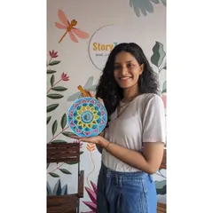 A happy participant holding her completed Lippan artwork against the backdrop of our studio wall. She was able to finish this entire decorative plate, from color choice to mirror placement, during a single session.