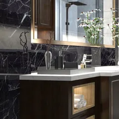 A close-up of a custom bathroom vanity set against a dramatic black marble wall. The design features a white countertop, dark wood cabinetry with an open display niche, and a large, gold-framed mirror.