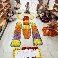 Our children, dressed in beautiful festive clothes, proudly pose with the Chandrayaan-themed flower rangoli they helped create for Onam.