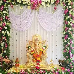 An elaborate floral backdrop for a Ganpati idol, using a variety of fresh flowers and a draped curtain to create a grand and divine setting.