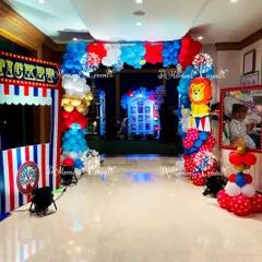 The entrance to the carnival party, complete with a ticket booth prop and a balloon arch featuring a circus lion, setting the stage for fun.