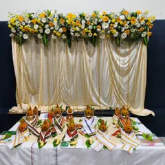 The pooja setup for a corporate 25th-anniversary event, with decorated coconuts placed in front of a beautiful floral backdrop.