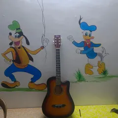 A new Henrix acoustic guitar finds its home in our classroom, ready for the next student, with Goofy and Donald Duck cheering on from the wall.