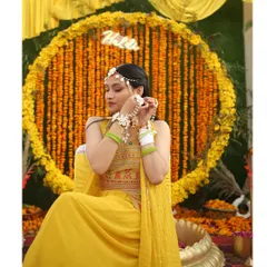 A close-up of the bride enjoying her Haldi function. The dense genda phool backdrop provides a perfect, vibrant setting for beautiful portraits.