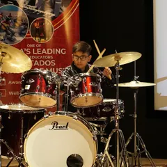 A young drummer focuses intently during his performance at the FSM Thane Recital. Our drum lessons cover everything from basic rhythms to complex solos, preparing students for powerful stage performances.