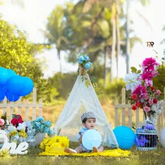 A wide shot of the outdoor setup, showing the baby playing with balloons in a beautiful, park-like setting. Outdoor sessions allow for natural, candid moments and beautiful light.