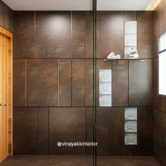 This shot highlights the beautiful contrast between the dark, textured wall panels and the intricate glass blocks inside the shower. The built-in niche provides convenient storage for toiletries.