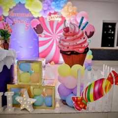 A close-up of the delightful props at Ravyanshi's Candyland party, including a giant cupcake, candy cutouts, and 'BABY' blocks filled with colorful balls.