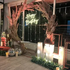 The rustic backdrop seen at night, with the neon sign, marquee letters, and fairy lights creating a warm and inviting glow.