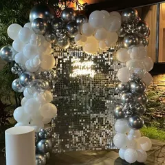 This outdoor setup features a beautiful silver shimmer wall framed by a white and chrome silver balloon arch. The way the sequins catch the light, especially in the evening, creates a magical, glittering effect perfect for any sophisticated party.
