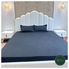 A modern bedroom setting featuring a bed with a scalloped, channel-tufted headboard in clean white. Paired with minimalist nightstands and elegant pendant lights, this design creates a chic and restful sanctuary.