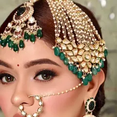 A model showcasing a beautiful passa, a traditional side-swept headpiece popular in Muslim weddings. This one features Kundan work with green bead drops.