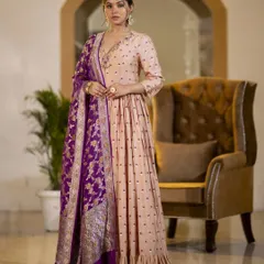 A model wearing a beautiful beige Anarkali gown with a contrasting purple Banarasi dupatta. This image showcases a complete ethnic ensemble, emphasizing the rich color combination and traditional weave.