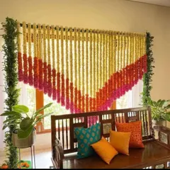 A simple and beautiful decoration for a pooja or small ceremony at home. A curtain of marigold and tuberose strings hangs behind a traditional wooden swing, creating a perfect sacred corner.