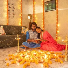 A sweet and intimate moment from a couple's Diwali shoot, as she rests her head on his shoulder, both seated amidst a sea of glowing diyas.