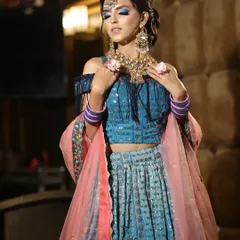 This stunning blue lehenga with a fringed, off-shoulder blouse is a perfect example of the modern party wear I offer. It's paired with a colorful Kundan and pearl jewellery set.