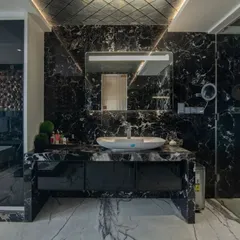 We believe bathrooms should be personal sanctuaries. This master bathroom uses dramatic black marble, bookmatched for continuous veining, and strategic lighting to create a bold, spa-like experience that feels both opulent and intimate.