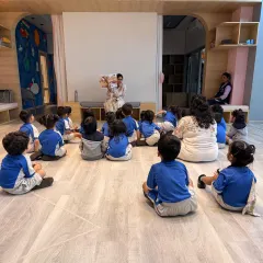 Even in a group, every child is captivated during storytime. Here, we're exploring the delightful book "How Do Dinosaurs Say Goodnight," showing that my sessions balance high energy with moments of focused calm and listening.