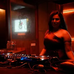 In the zone behind the decks, surrounded by the warm, ambient lighting of the club. This is my space, where I craft the musical journey for the night.