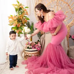 A tender moment between mother and son. Dressed in a magnificent pink tulle gown, this mother-to-be shares a flower with her son, a beautiful symbol of their growing love.