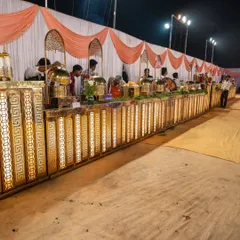 A wide view of my special royal setup for a wedding in Panvel. The long, illuminated golden counter creates an impressive and luxurious buffet line for guests.