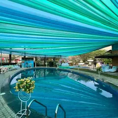 A unique poolside Haldi ceremony setup. We installed a flowing canopy of blue and green fabric over the pool, complementing the water and creating a beautiful, shaded space for the event.