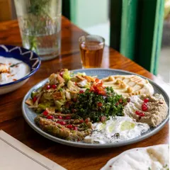 A close-up of the vibrant mezze platter at Cafe Zubaan. Natural light from the window highlights the freshness of the ingredients, making the dish look incredibly appetizing for their menu.